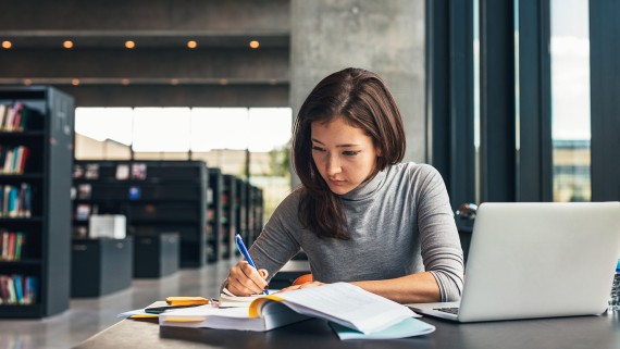 Vrouw studeert met laptop in bibliotheek
