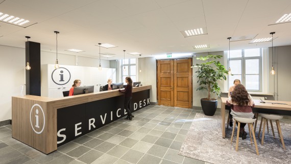 Een vrouw vraagt iets bij een servicedesk