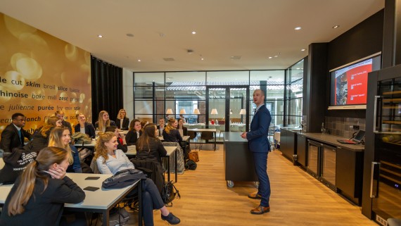 Een docent staat voor een lokaal met studenten