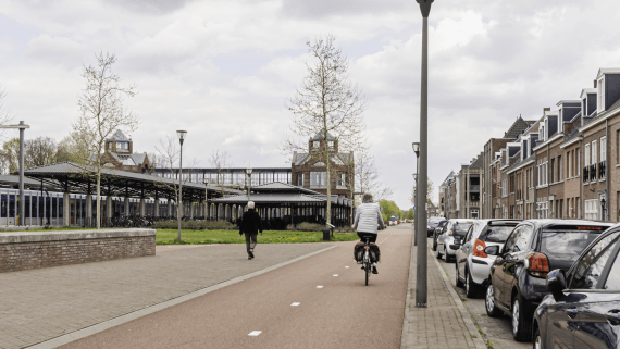Mensen fietsen en wandelen langs geparkeerde auto's