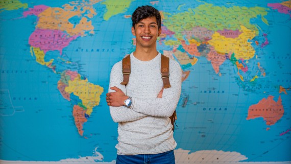 Een student staat voor een wereldkaart 