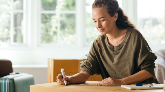 Een vrouw schrijft iets op een ingepakte verhuisdoos