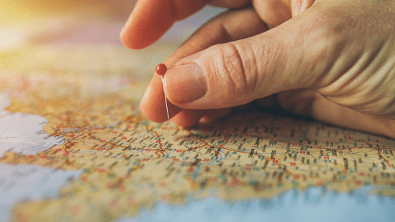 Een hand plaatst een speld op een kaart