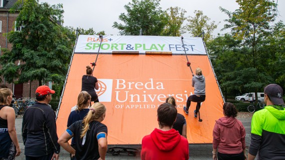 Twee studenten beklimmen een touw aan een muur