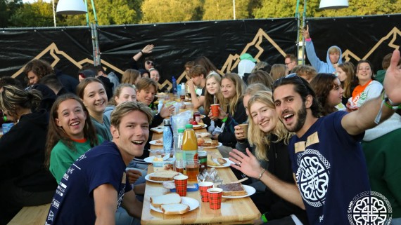 Lachende studenten eten samen aan lange tafels 