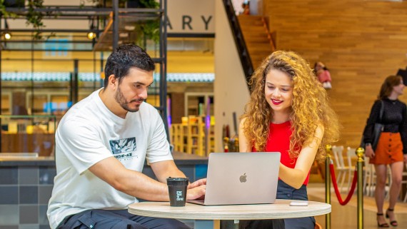 Twee studenten kijken samen op een laptop