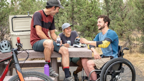 Een rolstoelgebruiker met twee anderen bij een picknicktafel