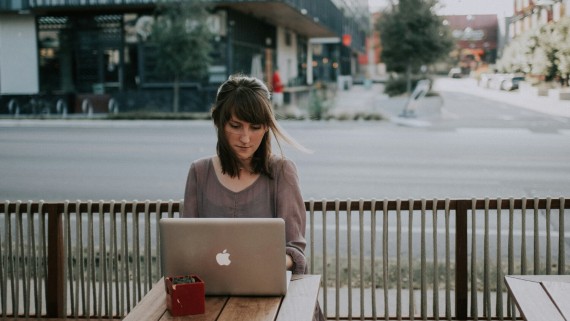 Een vrouw werkt op een laptop op een terras