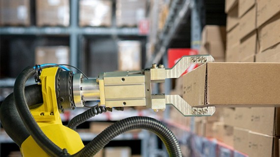 Een robot grijpt een kartonnen doos uit een stapel