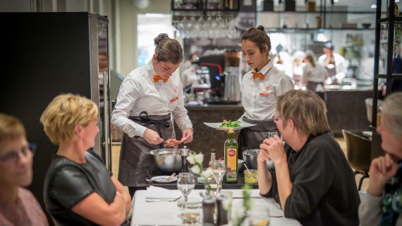 Twee studenten dienen borden op in een restaurant 
