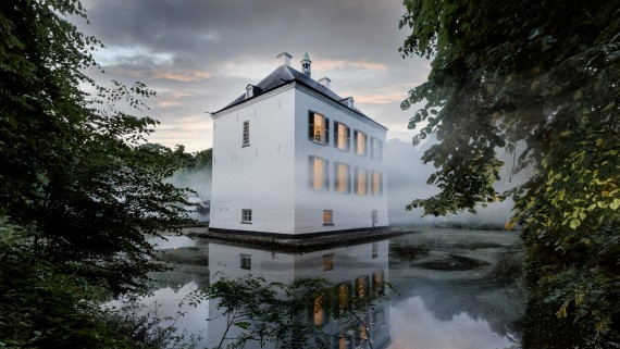 Een wit huis staat in het midden van een meer in een bos