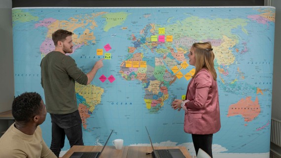 Twee studenten staan bij een grote wereldkaart