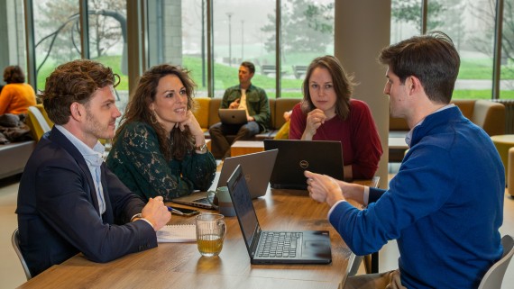 Vier mensen overleggen aan een tafel