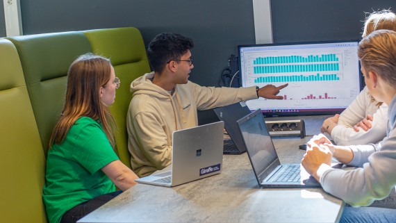 Een student toont medestudenten iets op een beeldscherm