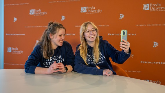 Twee student ambassadors lachen voor een telefoon