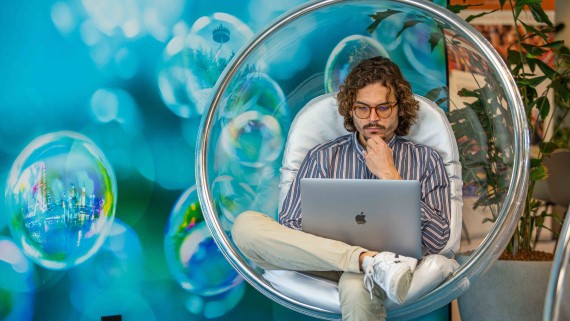 Student in een hangstoel werkt op een laptop