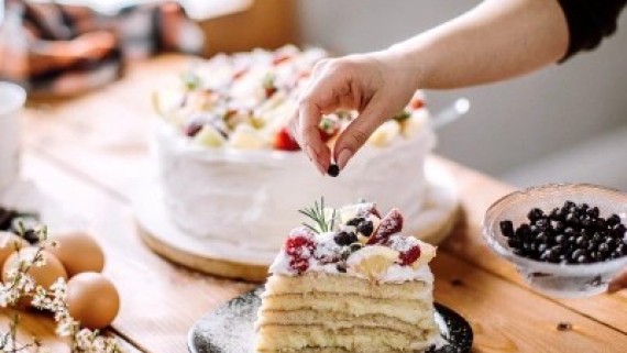 Een vrouw legt fruit op een taart