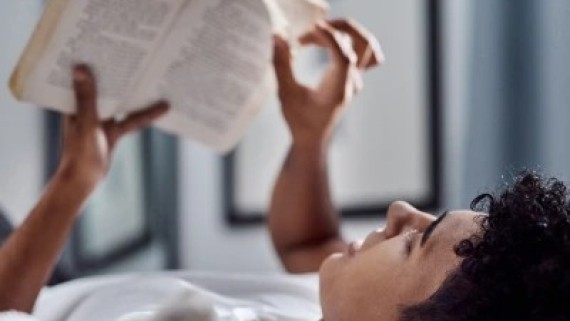 Een jongen leest een boek in bed