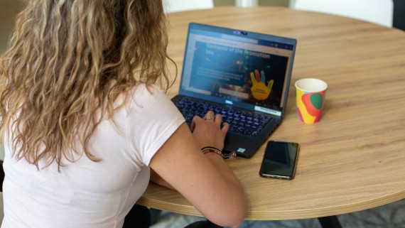 Student zit aan tafel achter haar laptop te werken