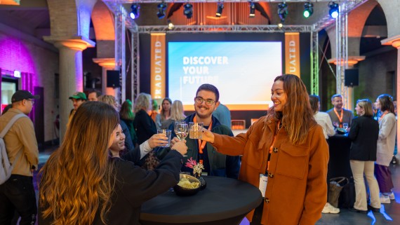 Mensen op een event proosten met elkaar aan een statafel 