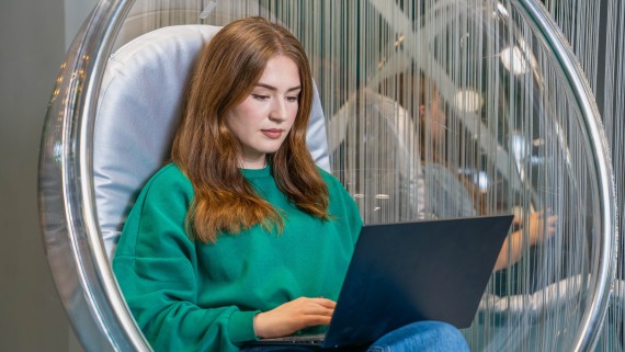 Student in een hangstoel met laptop op schoot