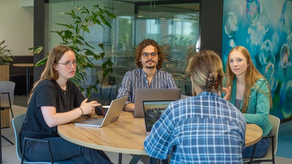 Vier studenten zitten aan tafel