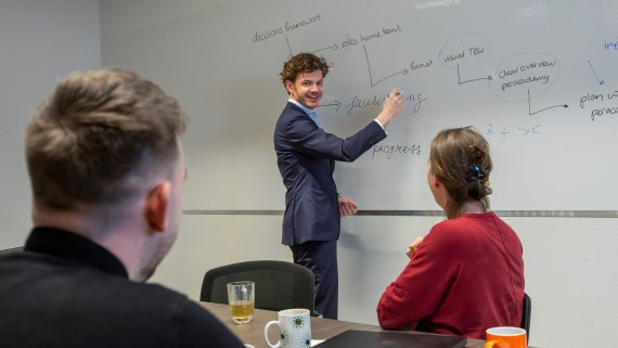 man writing on whiteboard educating colleagues