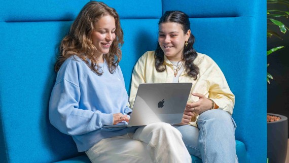 two students on a bench with a laptop
