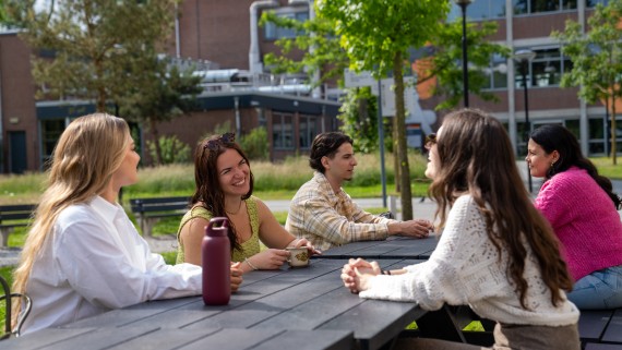 students at a picnic table sitting outside laughing