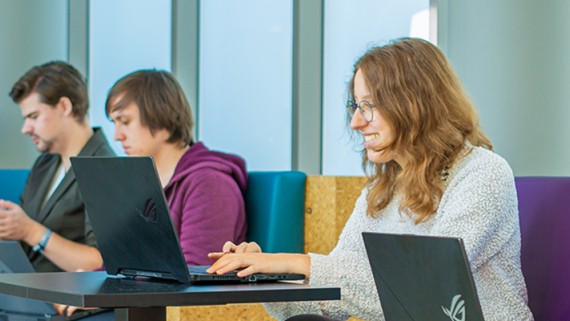 Vijf studenten werken op hun laptops op een bank