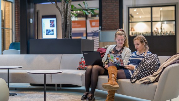 Twee studenten werken op laptops op een bank
