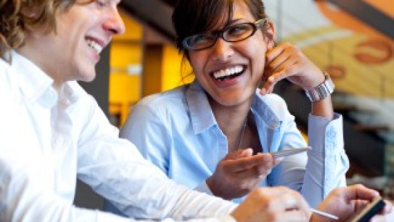 Twee lachende studenten zitten naast elkaar