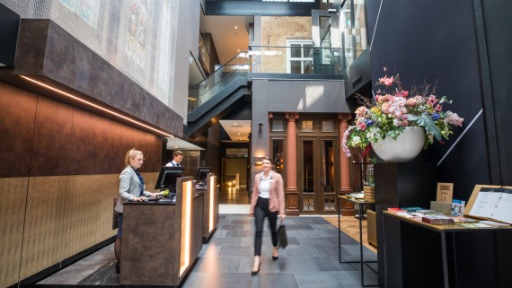 Een vrouw loopt langs een balie met twee medewerkers 