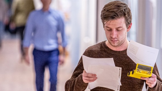 Een man kijkt naar papieren in zijn hand