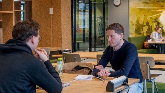 Studenten werken in een ruimte met tafels, stoelen en banken