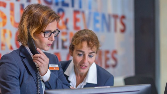 Twee vrouwen staan met een telefoon achter een balie