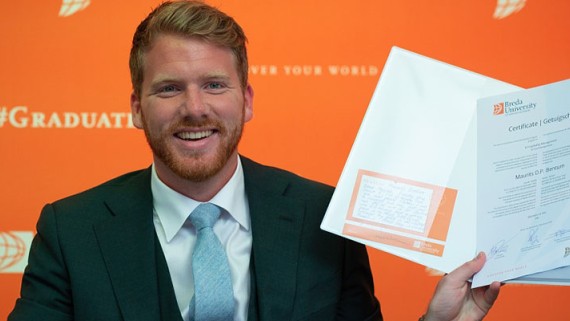 Een student houdt een BUas diploma vast