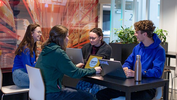 Vier studenten werken met hun laptop aan een tafel