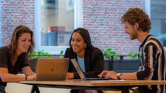 Studenten lachend achter een computer