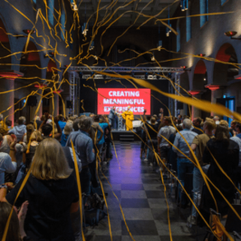 Linten vliegen door een zaal met een publiek en een podium