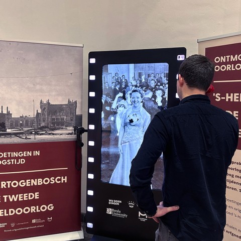 Een man bekijkt een scherm bij een expositie over de oorlog