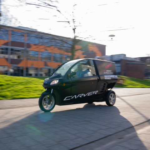 Een auto op drie wielen rijdt over de BUas campus