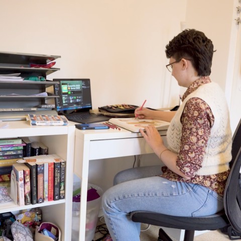 Een student werkt aan een bureau in haar studentenkamer