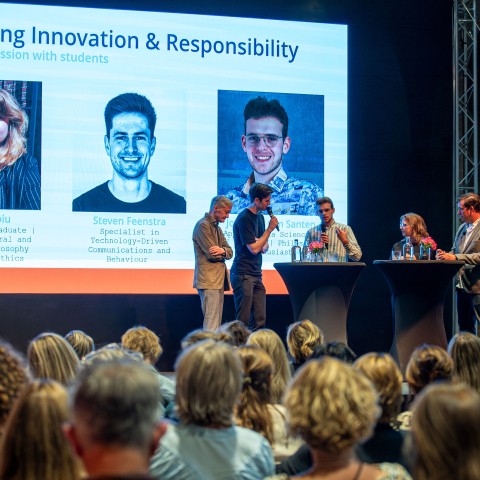 Vijf mensen geven een presentatie voor een grote zaal