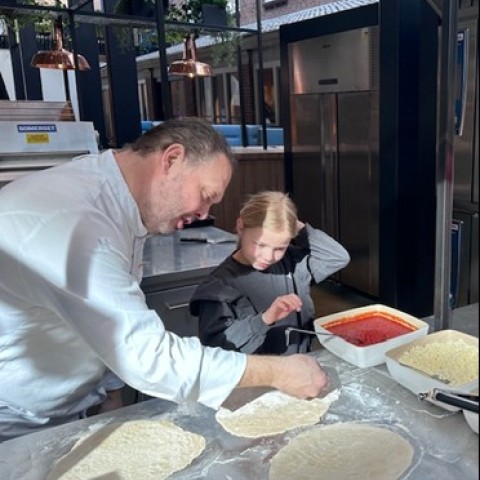 Kok legt aan kind uit hoe je een pizza maakt