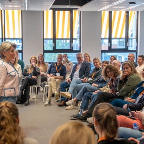 Een vrouw staat voor een groep zittende mensen