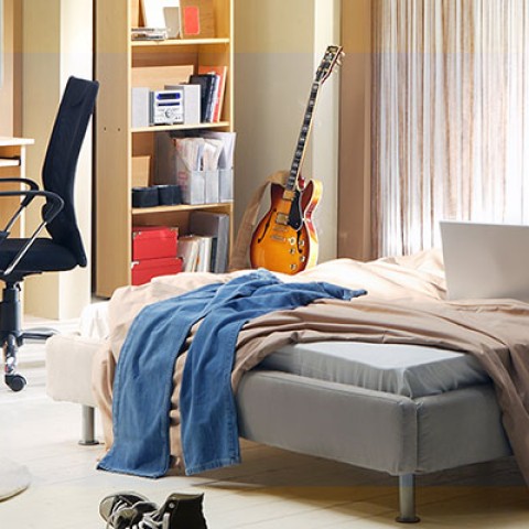 Een rommelige slaapkamer met een bed, bureau en stoel