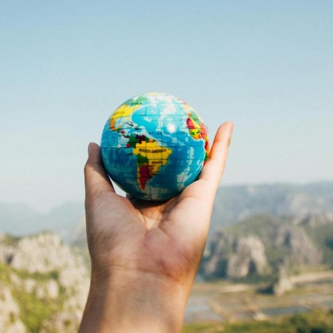 Een hand houdt een kleine wereldbol vast