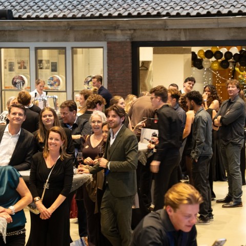 Gasten van het event luisteren naar het bekendmaken van de opbrengst van het charity dinner