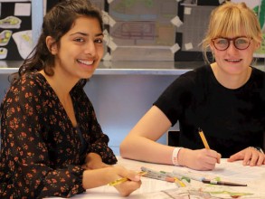 Twee studenten werken aan een ontwerp aan een tafel